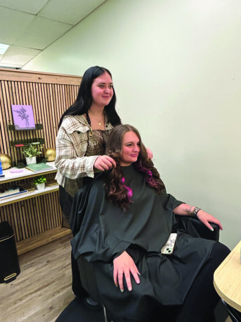 A happy Grace shares her work with Megan Geier when she’s finished. Megan waited a whole year for Grace to recover from her accident and be able to cut her hair again. Photo by Wanda Hanson