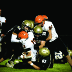 Caledonia defenders Cooper Allen (#52), Anthony VonArx (#75), and Charlie Mauss (#57) combine to take down St. Charles’ Bryndon Koeppel. The Warriors rallied from a tough week one loss by taking it to the Saints 40-18 in week two. Photo by Craig Johnson