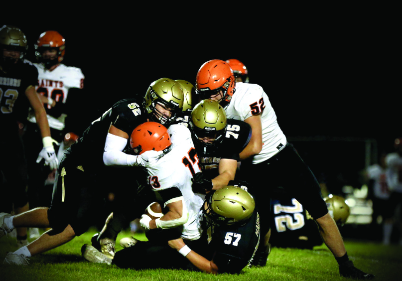 Caledonia defenders Cooper Allen (#52), Anthony VonArx (#75), and Charlie Mauss (#57) combine to take down St. Charles’ Bryndon Koeppel. The Warriors rallied from a tough week one loss by taking it to the Saints 40-18 in week two. Photo by Craig Johnson