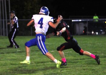 Mabel-Canton quarterback Isaac Underbakke gives Spring Grove defender Ezra Konkel a stiff-arm on the former’s 34-yard first half TD run (one of three scores for Underbakke in the game). The South-East leading #4 in 9-Man Cougars (6-0, 6-0) won 26-20, only their second win since 2010 versus the Lions. Photo by Paul Trende