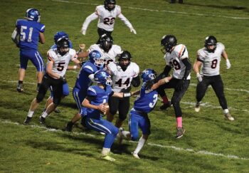 Mabel-Canton’s Isaac Underbakke looks to pass while getting a block from teammate Kale Eiken on Lanesboro’s Liam Miller (#29). Burros David Harvey (#5), Jackson Hearon (#56), Jack Lawston (#55), and Cooper Hovland (#8) lurk. M-C won the playoff quarterfinal 24-0. Photo by Heather Kleiboer