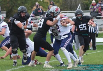 Fillmore Central defender William Boettcher has United South Central’s Kolt Bullerman in his grasp while Falcons Joseph Otto (#77) and Jeramiah Bushman (#55) look to help on the tackle. FC topped the Rebels 34-7 to move on to their fifth straight 1A title game. Photo by Paul Trende