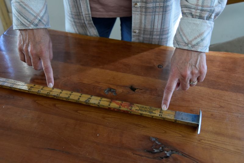 Jenny Kleppe demonstrates how to scale a log, which means to measure a log to determine its volume and quality. Photo by Charlene Corson Selbee