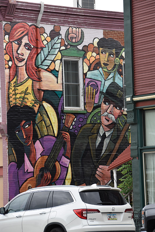 The Theatre District Mural, designed by Erik Pearson and completed in 2019, was painted on canvas-like material and applied similarly to applying wallpaper. It is displayed on the side of the Commonweal Theatre Company in Lanesboro. Photo by Charlene Corson Selbee