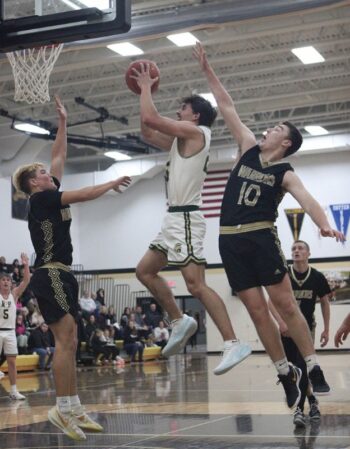 Rushford-Peterson’s Landon Dahl takes it to the hoop as Caledonia’s Aaron Stemper (right) and Zeke Gengler (left) are nearby defensively. The reloaded Warriors notched a key early season TRC win, topping the Trojans 71-64. Photo by Paul Trende