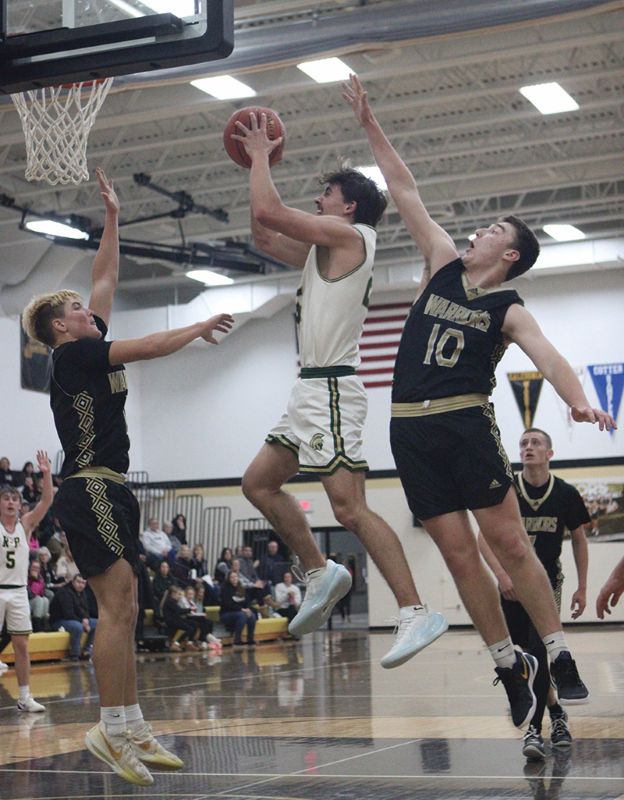 Rushford-Peterson’s Landon Dahl takes it to the hoop as Caledonia’s Aaron Stemper (right) and Zeke Gengler (left) are nearby defensively. The reloaded Warriors notched a key early season TRC win, topping the Trojans 71-64. Photo by Paul Trende