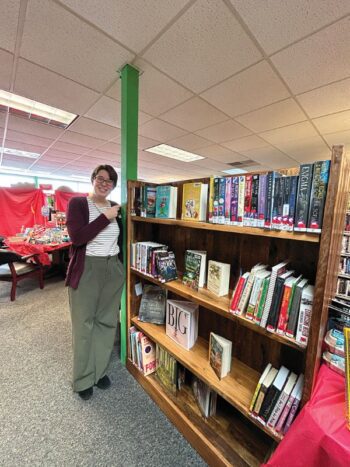 Cara points out the location of the newly arrived books at the middle of the library. Photo by Wanda Hanson