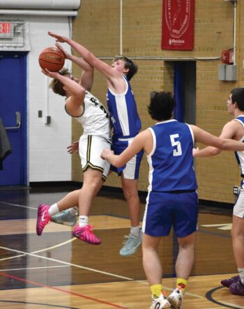 Mabel-Canton’s Brevyn Tollefsrud defends the shot of Rushford-Peterson’s Jaxson Meldahl in the Trojans’ 76-56 win. Photo by Heather Kleiboer