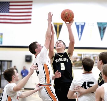 Caledonia’s Coby Hammell looks for the lefty flip-shot on St. Charles Cade Delger in the Warrior and Saints’ TRC battle, won by the Saints 63-61 on a shot in the final three seconds. Photo by Craig Johnson