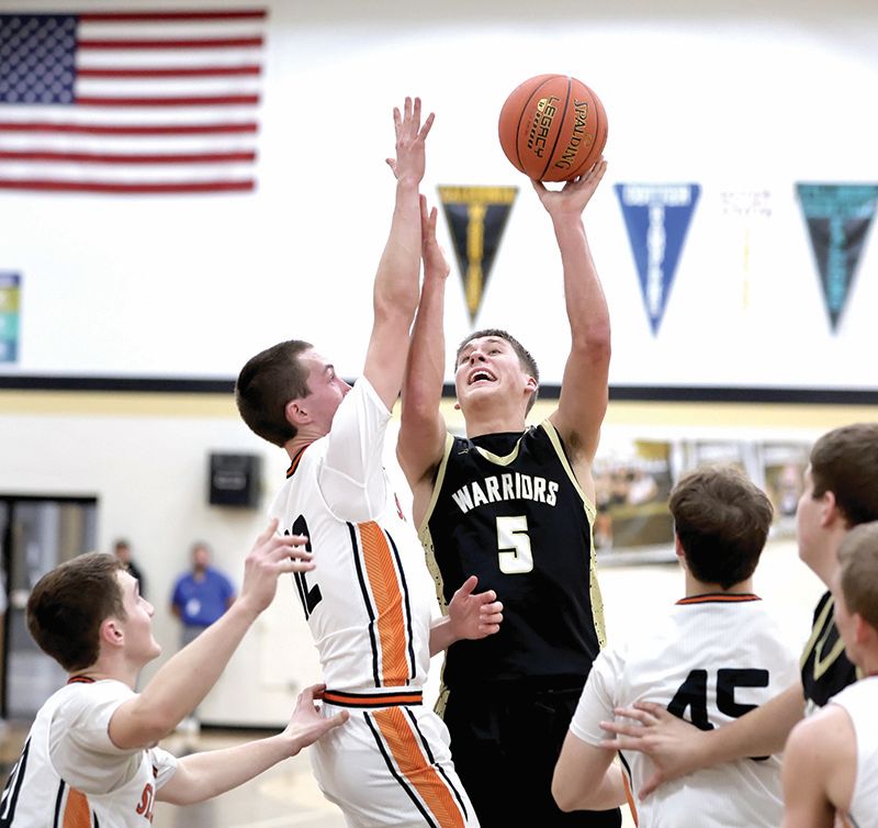 Caledonia’s Coby Hammell looks for the lefty flip-shot on St. Charles Cade Delger in the Warrior and Saints’ TRC battle, won by the Saints 63-61 on a shot in the final three seconds. Photo by Craig Johnson