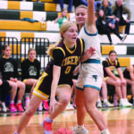 Rushford-Peterson’s Alannah Skalet (wearing a Peterson Tigers jersey) goes baseline closely defended by Fillmore Central’s Aubrey Daniels. FC led most of the game but survived a Trojan comeback to prevail 87-85 in overtime in a fiercely fought contest. Photo by Paul Trende