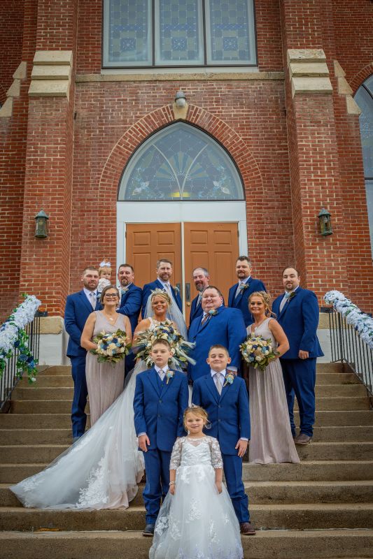 Wedding party on the church steps. In front is flower girl Laramie Lind. Second row: Tate and Channing Lind, junior groomsmen. Third row: Taresa Tweeten, maid of honor; newlyweds Jaclyn and Ryan; Tracy Lind, matron of honor. Fourth row: Tim Morken, usher; Legacy Lind, flower girl; Colby Lind, groomsman; John Koons, groomsman; Tyler Hahn, best man; Cody Palen, groomsman; Reid Shipman, usher. Photo by Bluestem Films LLC