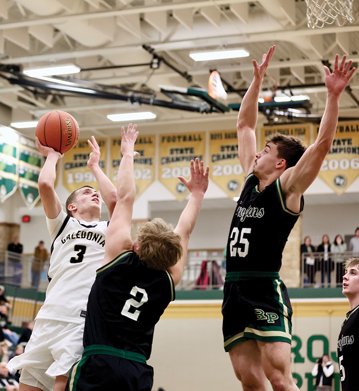 R-P’s Landon Dahl goes high to block the shot of Caledonia’s Grant King while Trojan Jaxson Meldahl (#2) provides on ball defense. In a key TRC-East matchup, the Trojans (9-2, 17-3) posted an 86-64 win to take sole possession of first place over Cotter/HL (9-3, 16-7) and the Warriors (8-3, 12-7). Photo by Craig Johnson