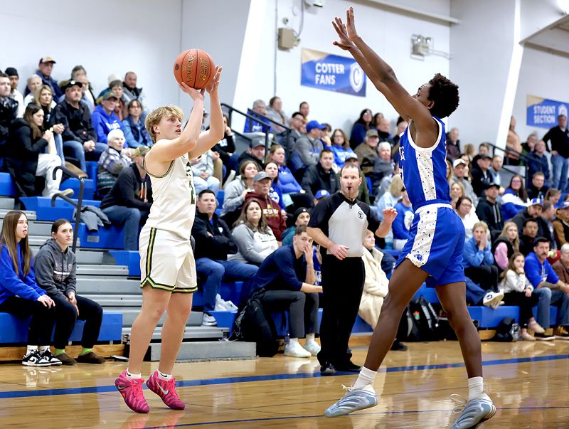 Rushford-Peterson’s Jaxson Meldahl takes a three over the advancing Gedion Errthum in the Trojans’ battle for first with Cotter/Hope Lutheran. Meldahl and Brode Vickerman supplied 11 first half bench points, helping the Trojans to a key 70-52 victory. Photo by Craig Johnson