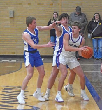 Grand Meadow’s Carter Glynn is hemmed in by Mabel-Canton defenders Nolan Garness and Cael Wangsness in the Cougars notable 79-47 SEC win. M-C improved to 10-5. Photo by Heather Kleiboer