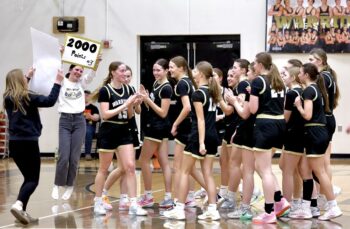 Caledonia managers hold up signs signifying senior Aubrie Klug (fourth player from left) and her accomplishment. Klug scored her 2,000th point in a Round of 16 playoff win over La Crescent/Hokah. Photo by Craig Johnson