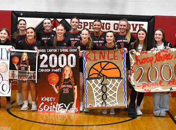 Spring Grove/Mabel-Canton’s Kinley Soiney (holding her own sign) poses with teammates after surpassing 2,000 career points in a Section 1A Round of 16 playoff win over Grand Meadow. Photo by Lee Epps