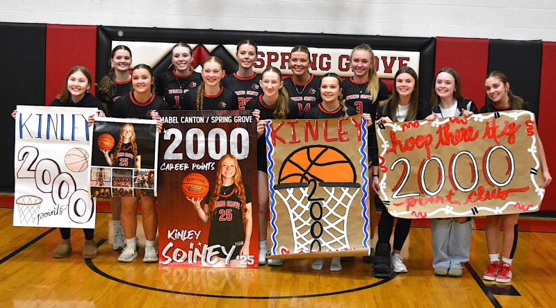 Spring Grove/Mabel-Canton’s Kinley Soiney (holding her own sign) poses with teammates after surpassing 2,000 career points in a Section 1A Round of 16 playoff win over Grand Meadow. Photo by Lee Epps
