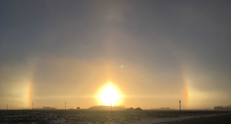 They were barking. Sundogs or parhelia, are bright, colorful patches of light that appear roughly 22 degrees to one or both sides of the sun. They are created when sunlight bends (refracts) through ice crystals acting as a prism. They display color dispersion similar to rainbows, with red closest to the sun and blue on the outside.Photo by Al Batt