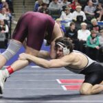 FCLMC senior Kane Larson uses his long arm to reach for the leg of Royalton/Upsala’s Jake Leners in a state title match at 189-pounds. Larson romped to the state title, winning his six post-season bouts by a combined 102-17 tally to become the Wolves’ first two-time state champion. Photo by Paul Trende
