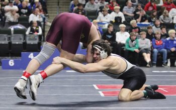 FCLMC senior Kane Larson uses his long arm to reach for the leg of Royalton/Upsala’s Jake Leners in a state title match at 189-pounds. Larson romped to the state title, winning his six post-season bouts by a combined 102-17 tally to become the Wolves’ first two-time state champion. Photo by Paul Trende