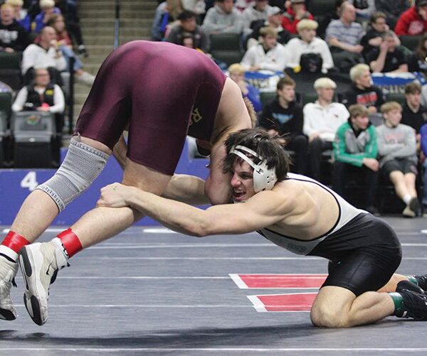 FCLMC senior Kane Larson uses his long arm to reach for the leg of Royalton/Upsala’s Jake Leners in a state title match at 189-pounds. Larson romped to the state title, winning his six post-season bouts by a combined 102-17 tally to become the Wolves’ first two-time state champion. Photo by Paul Trende