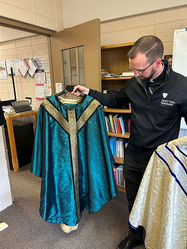 Fr. Nicholas looks at the blue chasuble and stole as he explains their significance. Photo by Wanda Hanson