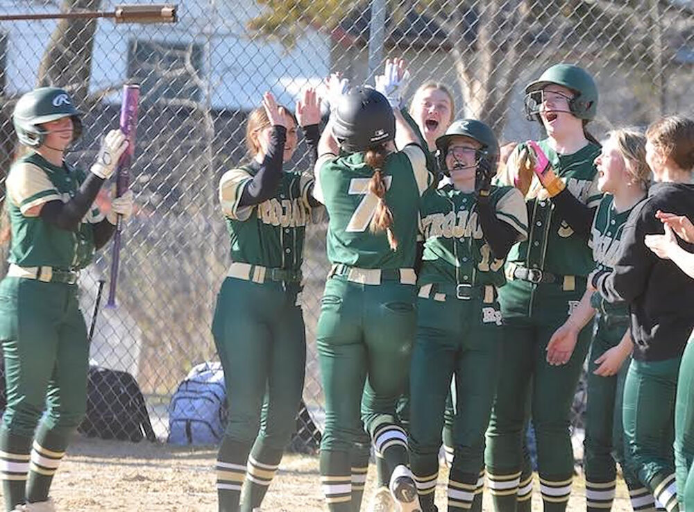 Rushford-Peterson’s Shelby Tesch (#7) gets congratulated at home plate after hitting a grand slam home run in the Trojans 8-2 win over the Lions, one where SG pitcher Claire Sherburne also struck out 19. Photo by Lee Epps