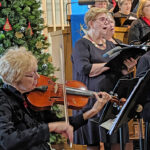 Karen Grandall not only works to help recruit new choir members, but is an accomplished vocalist, violinist, pianist, and violist with this photograph of her playing her viola accompanying the Bluff Country Singers. Photo by SimplyMary