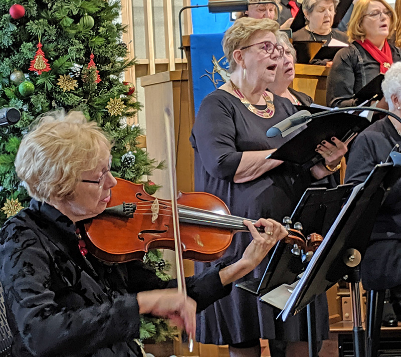 Karen Grandall not only works to help recruit new choir members, but is an accomplished vocalist, violinist, pianist, and violist with this photograph of her playing her viola accompanying the Bluff Country Singers. Photo by SimplyMary