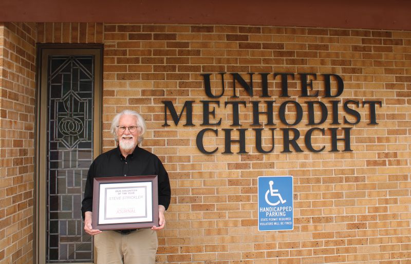 Steve proudly displays his award outside the Chatfield United Methodist Church, which now serves as a community outreach center since he started the food shelf in 2015. Photo by Jason Sethre